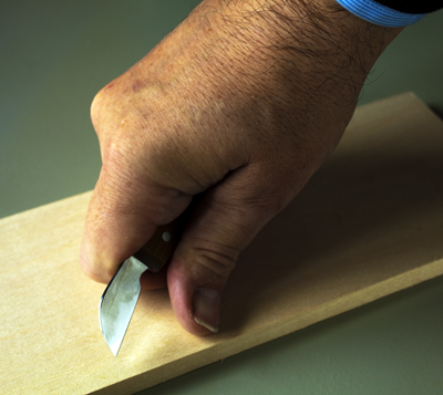 El cuchillo cortando un bisel en la tabla de prácticas