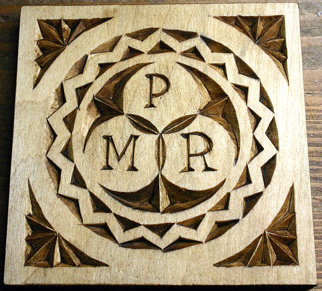 Talla geométrica con las letras P, M y R en un círculo