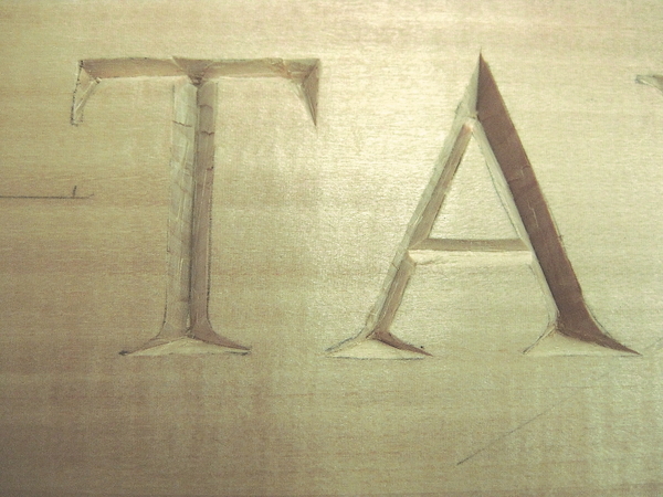 Detalle del tallado en bajorrelieve de la T y la A