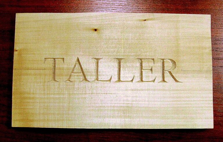 El letrero TALLER tallado en bajorrelieve sobre tabla de tilo