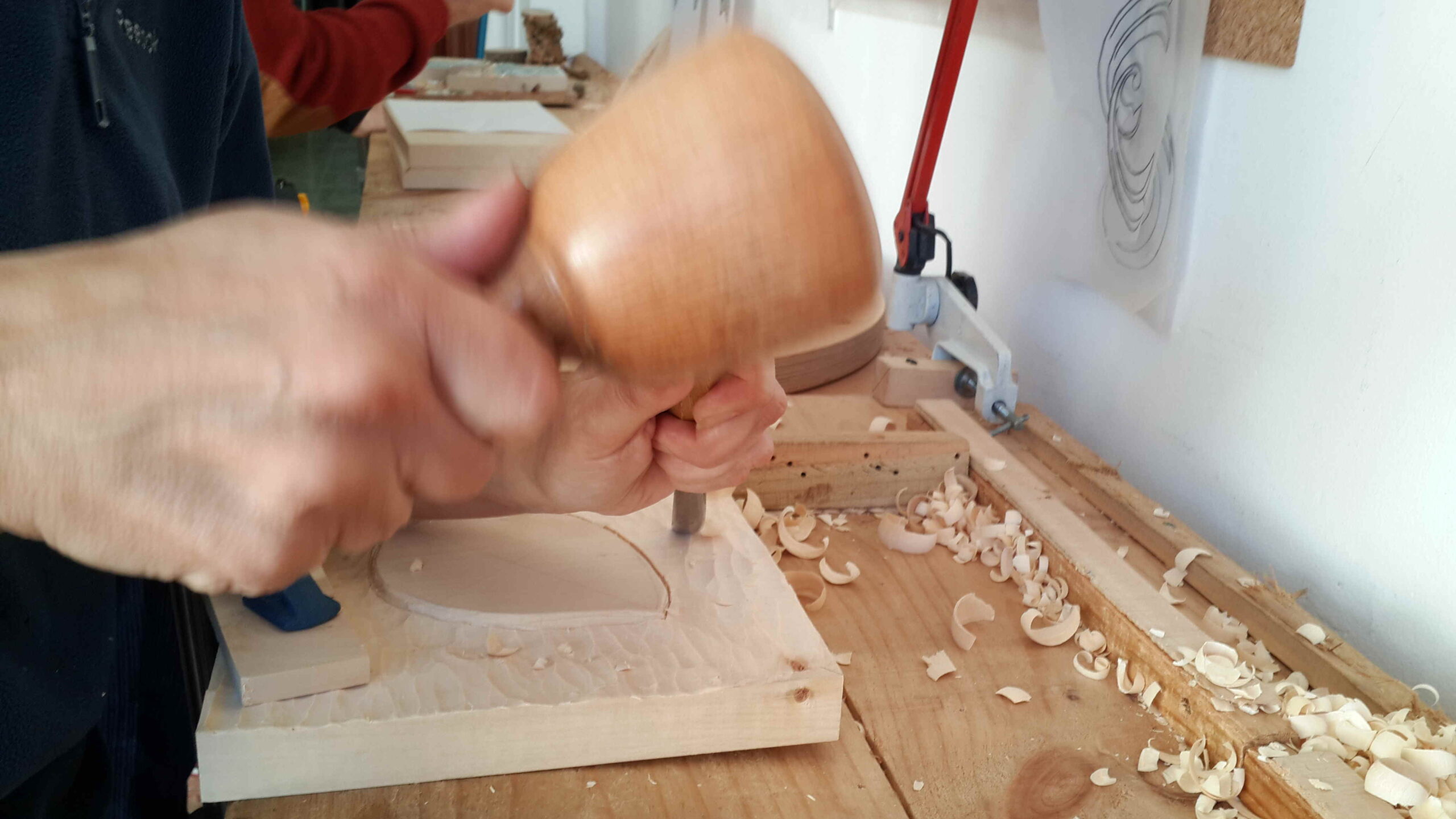 Manos tallando el contorno de una hoja en el taller